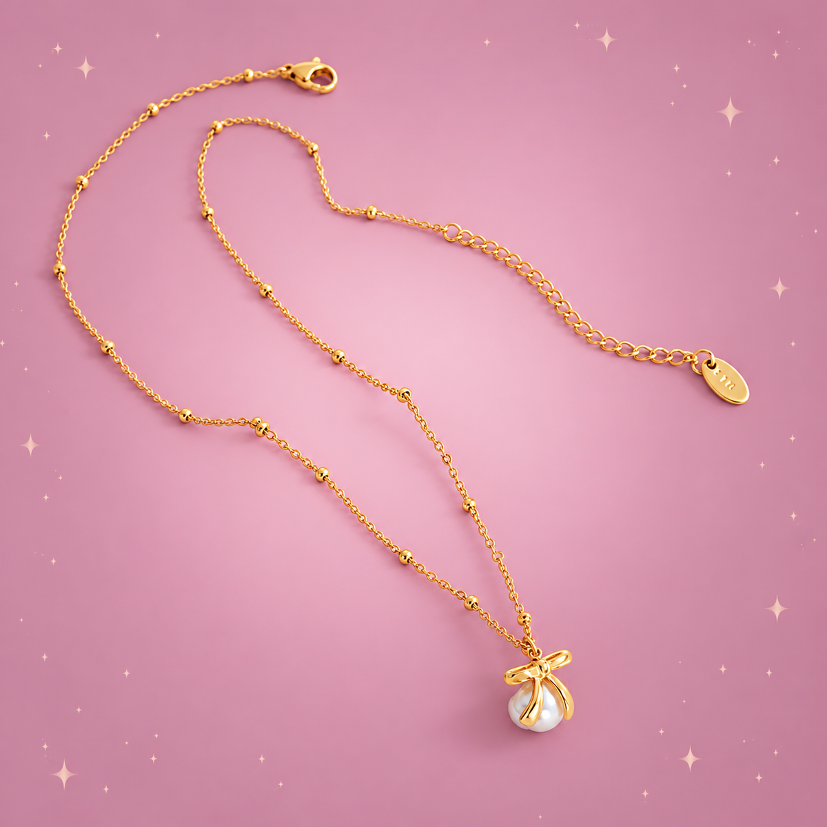 Bow & Bead Necklace on a dusty rose background with rose gold sparkles