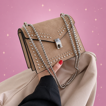 Chain & Rivet Crossbody Bag on a dusty rose background with rose gold sparkles