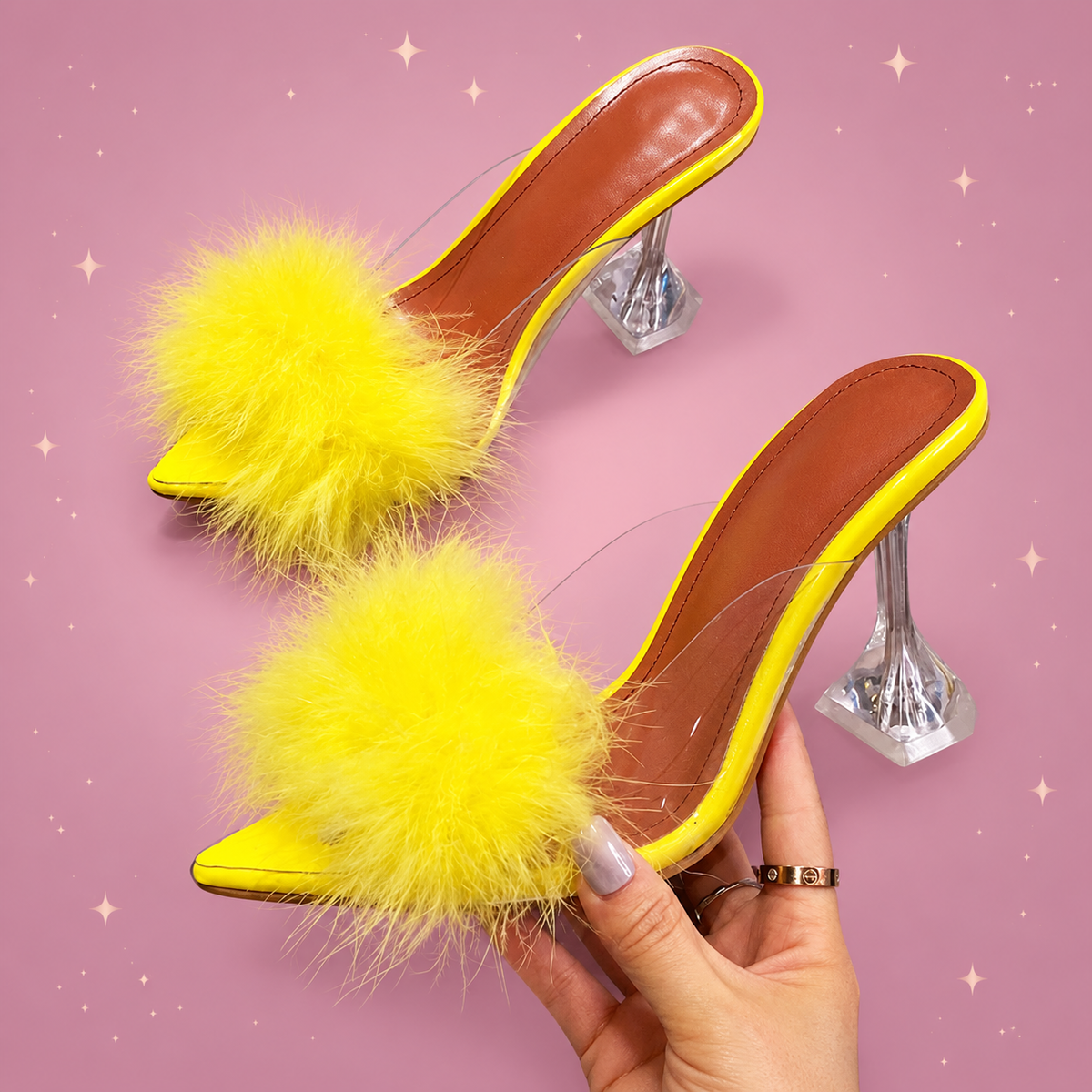 Clear Feather Heel Mules on a dusty rose background with rose gold sparkles