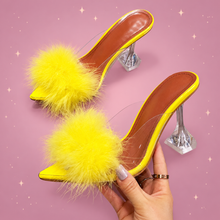 Clear Feather Heel Mules on a dusty rose background with rose gold sparkles