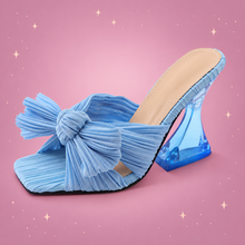 Satin Sculpted-Heel Sandals on a dusty rose background with rose gold sparkles