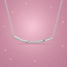 Silver Smile Necklace on a dusty rose background with rose gold sparkles