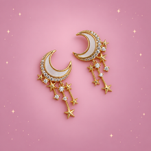 Star & Moon Drop Earrings on a dusty rose background with rose gold sparkles