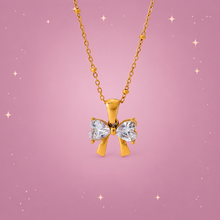 Zircon Bow Necklace on a dusty rose background with rose gold sparkles